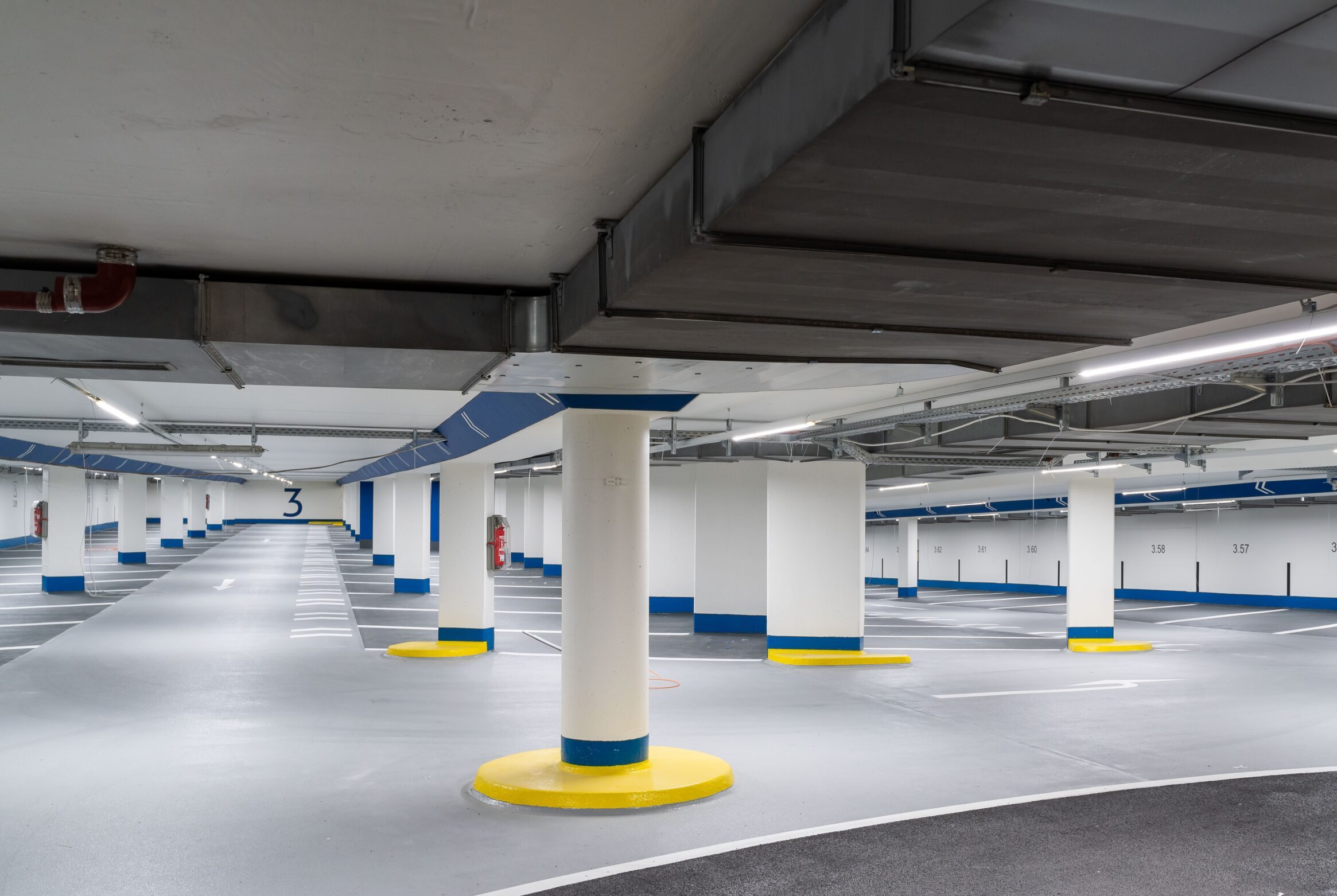 Blick in Parkebene 3 der Rostocker Tiefgarage City noch ohne Fahrzeuge, großzügig, hell und freundlich mit blauen und gelben Akzenten
