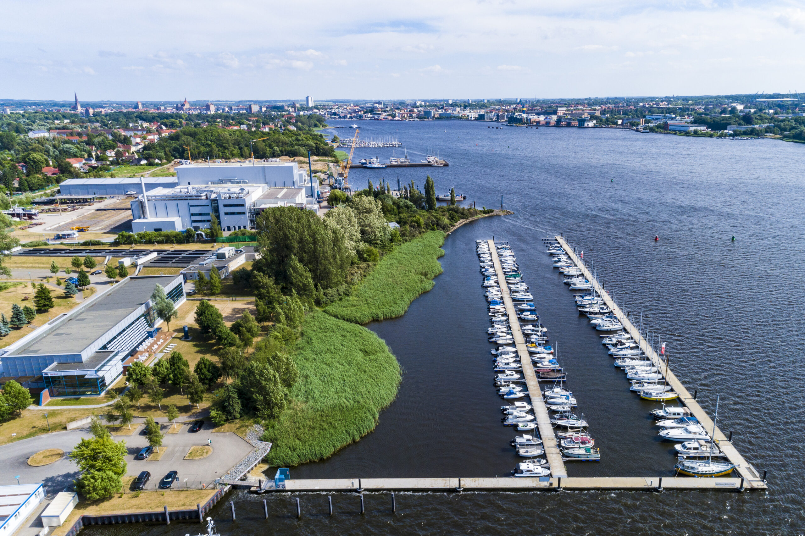 Luftbild mit Blick Richtung Osten auf die Marina und Steganlage Gehlsdorf an der Rostocker Warnow, Im Hintergrund die Rostocker Innenstadt und nebenan die Schwimmhalle Gehlsdorf